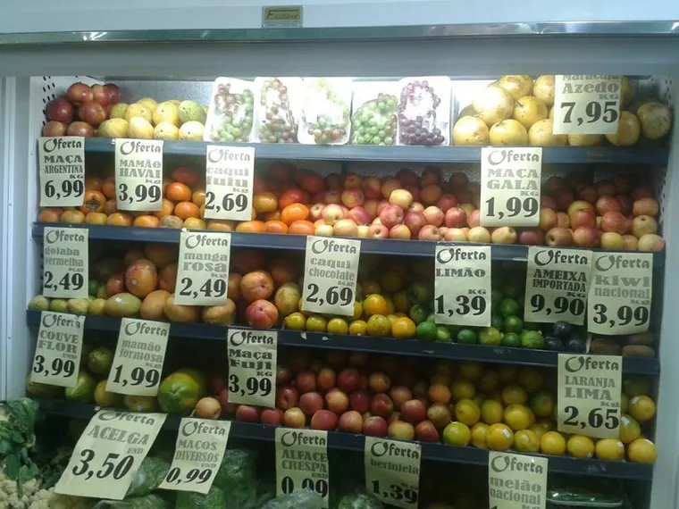 Gôndola de hortifruti abastecida, com etiquetas de oferta escritas à mão
